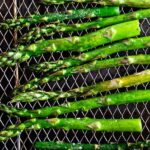 Overhead shot of asparagus on the air fryer rack with recipe title on bottom of photo