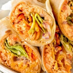 Buffalo chicken wraps cut in half and stacked on a plate with recipe title on bottom of image