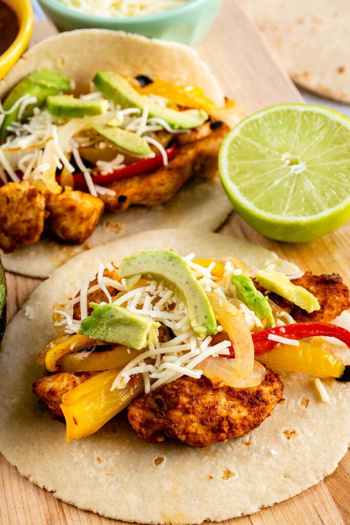 Two tortillas filled with sheet pan chicken fajitas, peppers, cheese and avocado