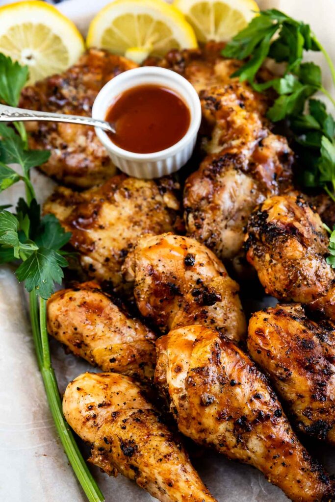Easy barbecue chicken with dipping sauce, lemon slices and parsley