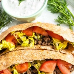 Close up shot of two ground beef gyros loaded with traditional gyro toppings