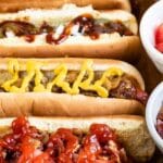 Close up overhead shot of hot dog bar with hot dogs and all the toppings with recipe title on the bottom of image