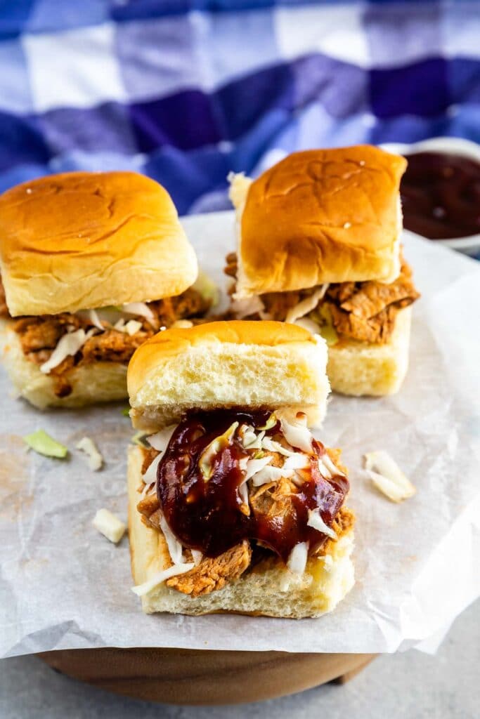 Three instant pot pulled pork sliders on parchment paper