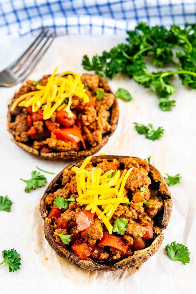 Two taco stuffed portobello mushrooms topped with shredded cheese