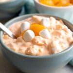 Two bowls of mandarin orange salad topped with mini marshmallows and mandarin oranges and recipe title on bottom of photo