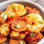 Bowl of spicy shrimp and sausage skillet over white rice with recipe title on bottom of image