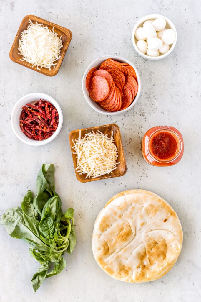 Overhead view of all ingredients and toppings for easy pita pizzas