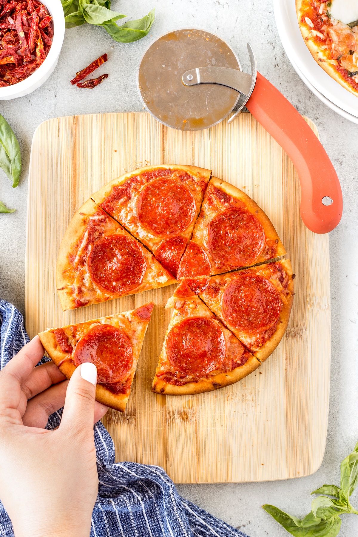 Overhead view of pepperoni pita pizza on a wooden cutting board