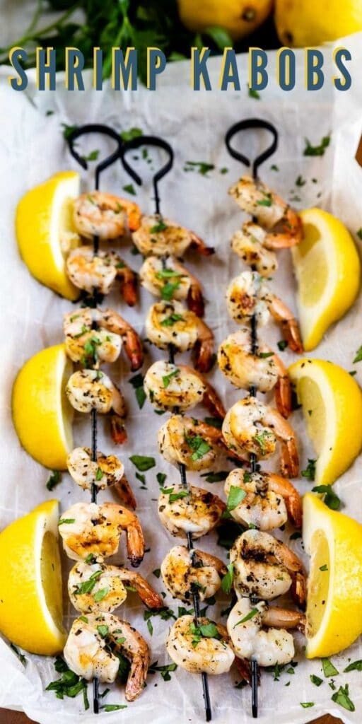 Overhead view of three skewers of shrimp kabobs surrounded by lemons with recipe title on top of image