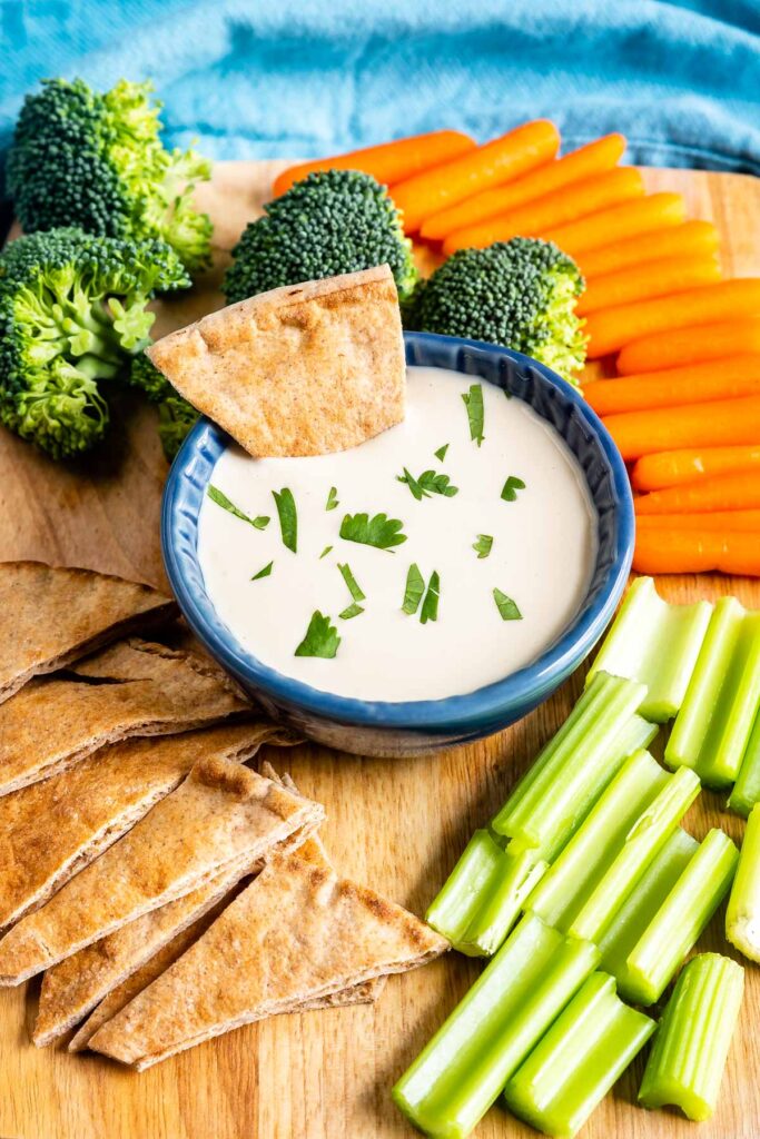 Overhead shot of tahini sauce in a dipping cup with a pita bread dipped in