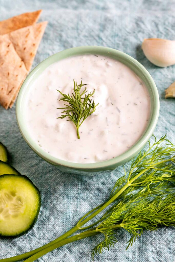 Overhead shot of a bowl of tzatziki sauce surrounded by ingredients