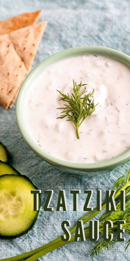 Overhead shot of a bowl of tzatziki sauce surrounded by ingredients and recipe title on bottom of photo