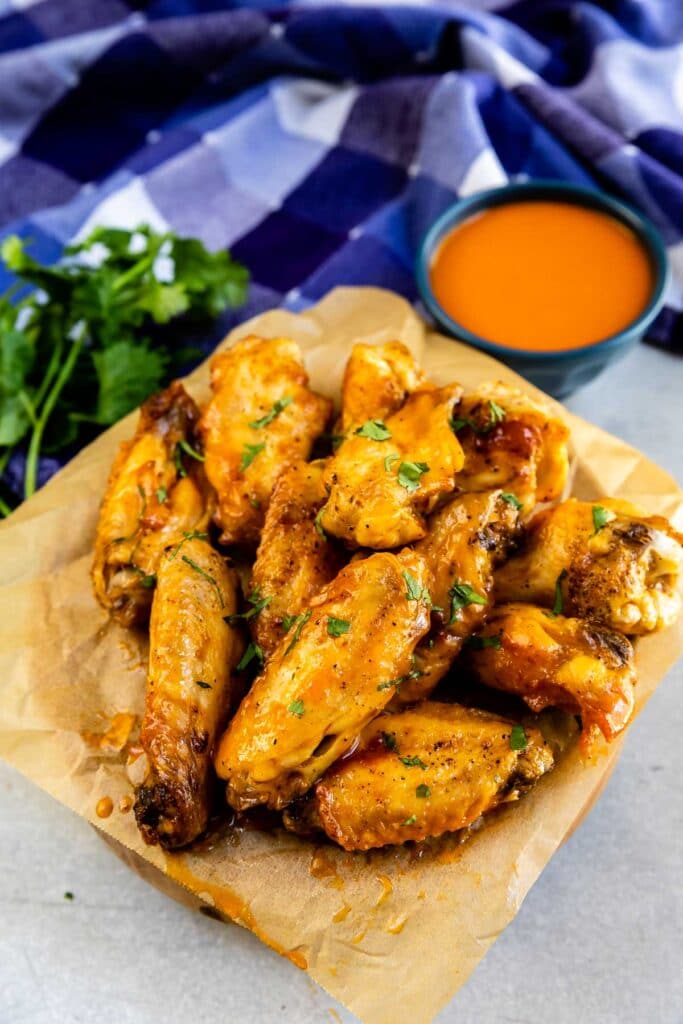 Overhead view of crispy air fryer chicken wings with buffalo sauce behind it
