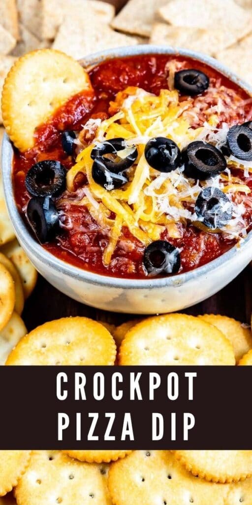 Crockpot pizza dip in a small bowl topped with cheese and olives and surrounded by crackers for dipping with recipe title on bottom of photo