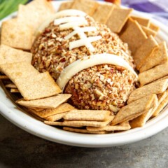 Football Cheese Ball on a serving plate surrounded by crackers
