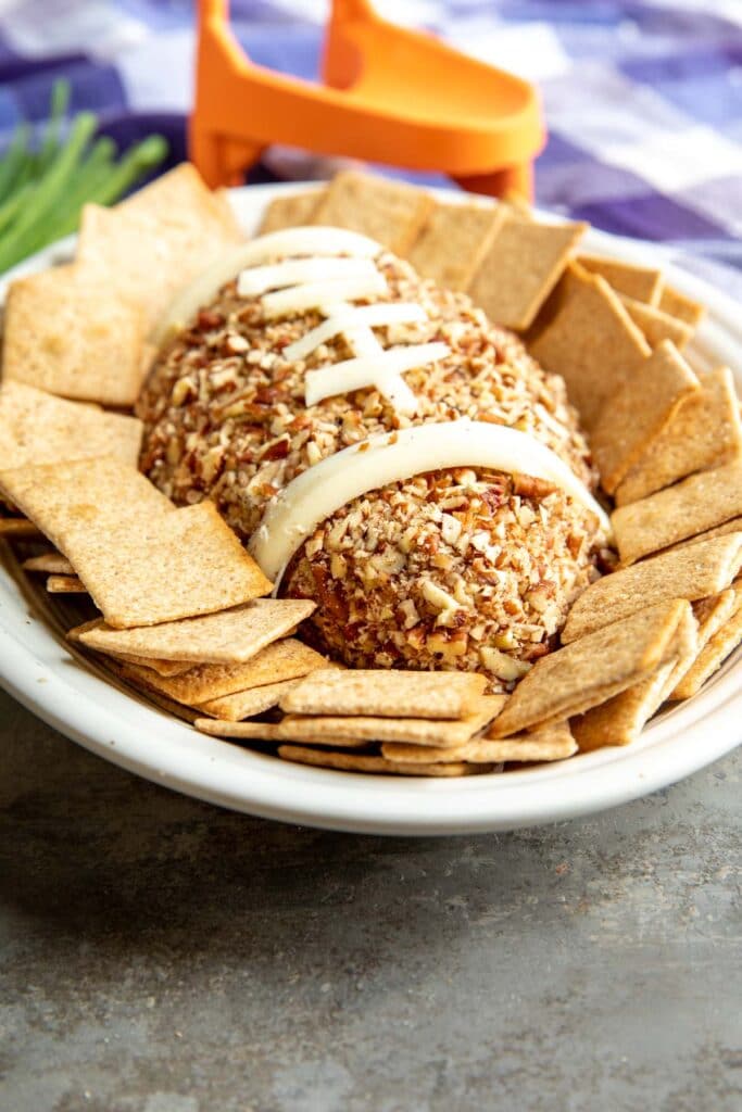 Football Cheese Ball on a serving plate surrounded by crackers