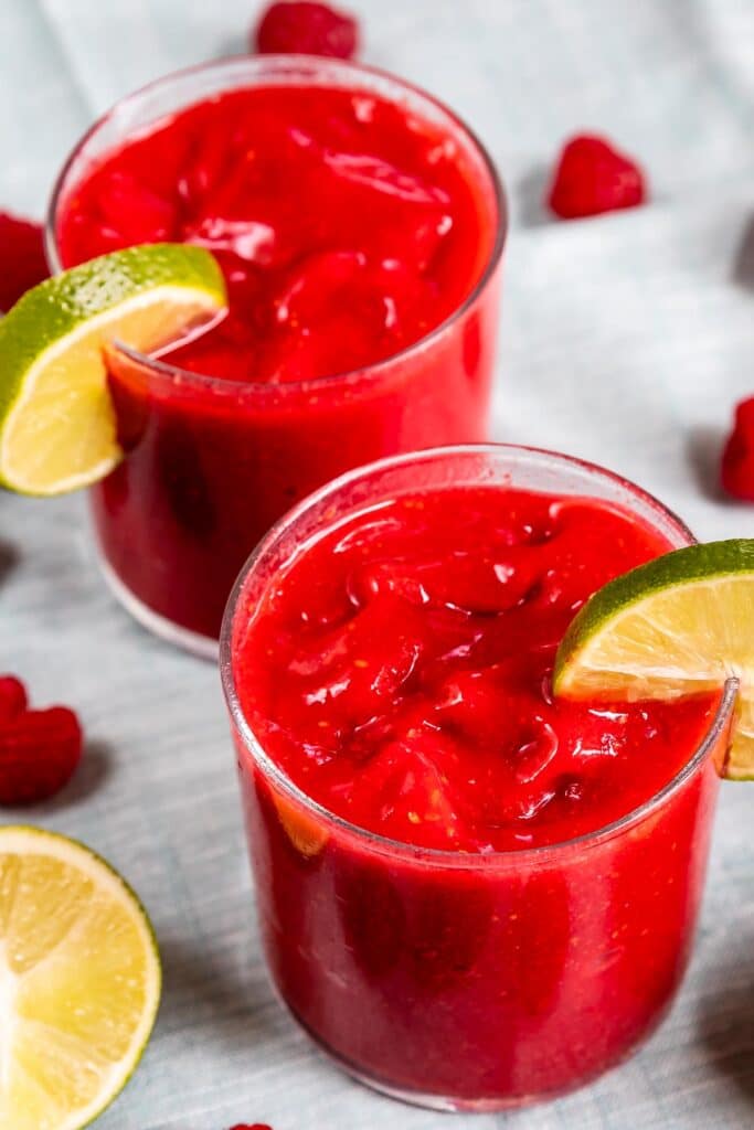 Two glasses of raspberry vodka slushies with lime wedge