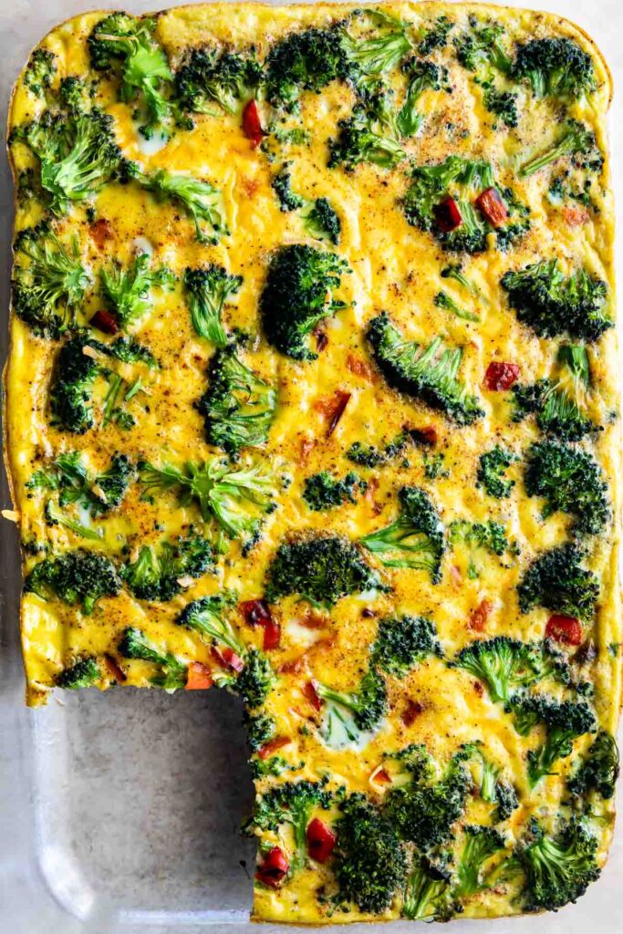 Overhead shot showing broccoli breakfast casserole in a dish with one corner piece missing