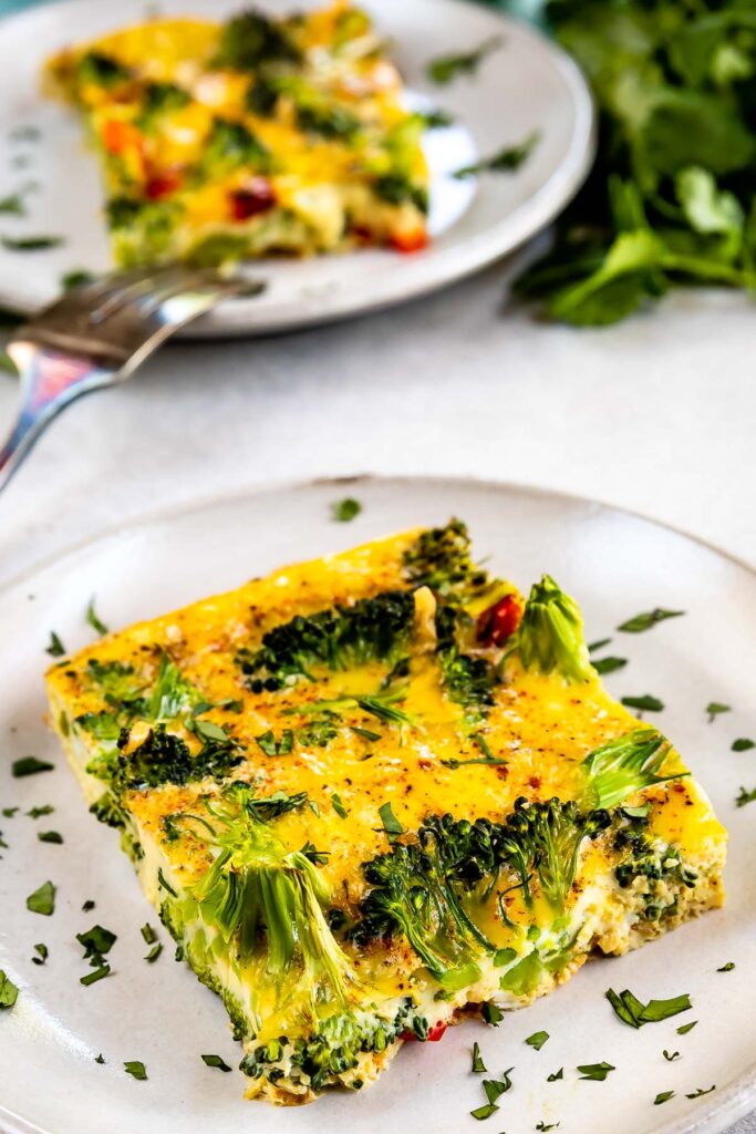 Two square pieces of broccoli breakfast casserole on plates next to eachother