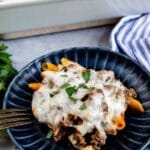 One serving of pasta casserole on a blue plate with recipe title on bottom of photo