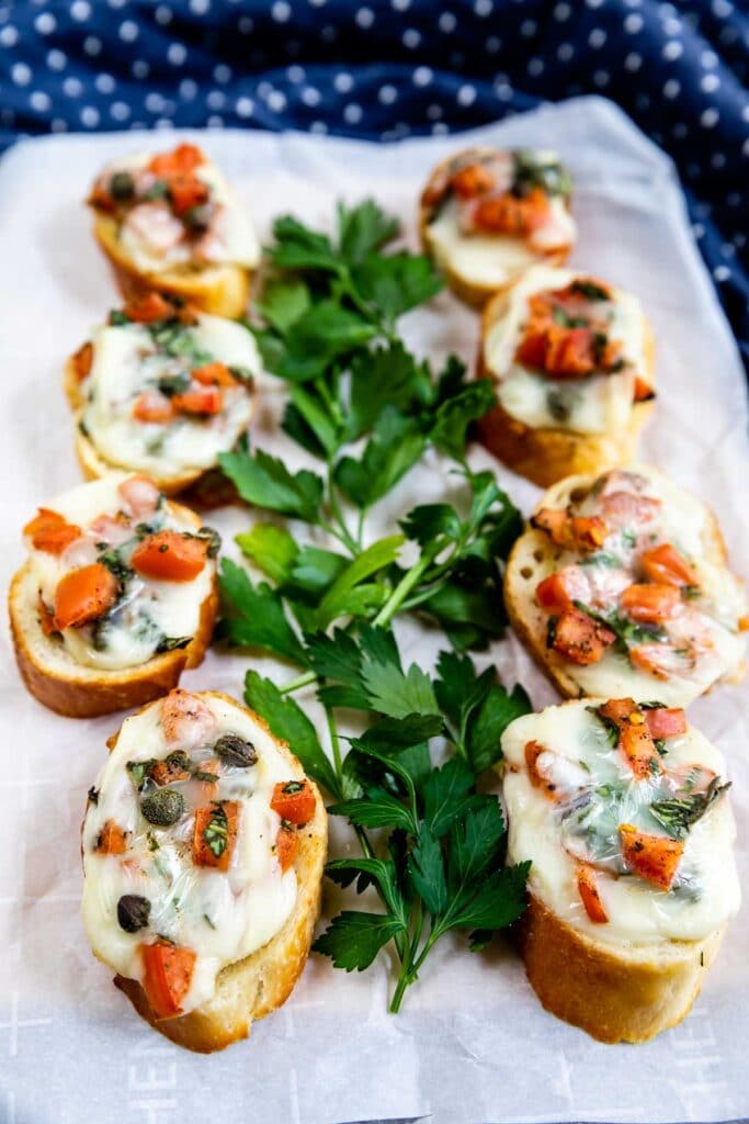 Two rows of crostini on a plate with herbs in the middle