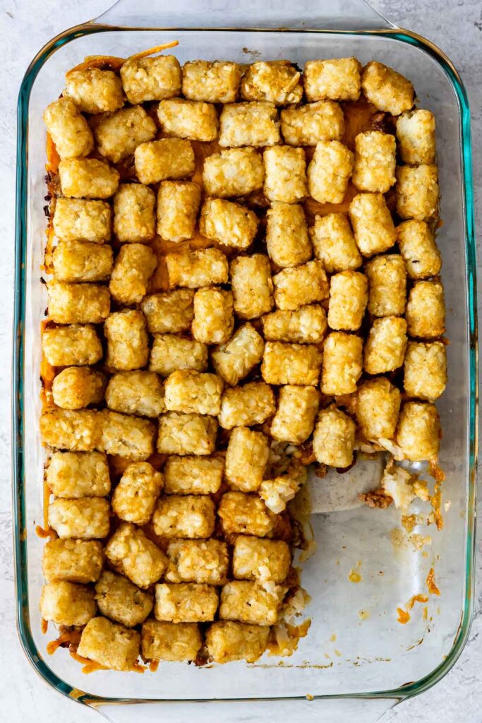 Overhead shot of tater tot and chili casserole in casserole dish with bottom right hand corner missing