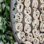 Overhead shot of tortilla pinwheels on a serving platter with recipe title on bottom of photo