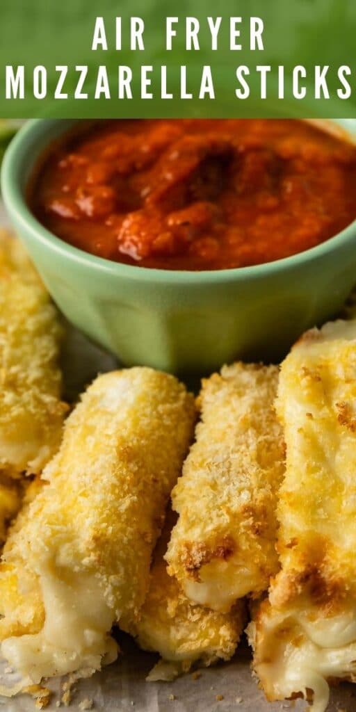 Close up shot of air fryer mozzarella sticks next to a small bowl of marinara sauce and recipe title on top of image