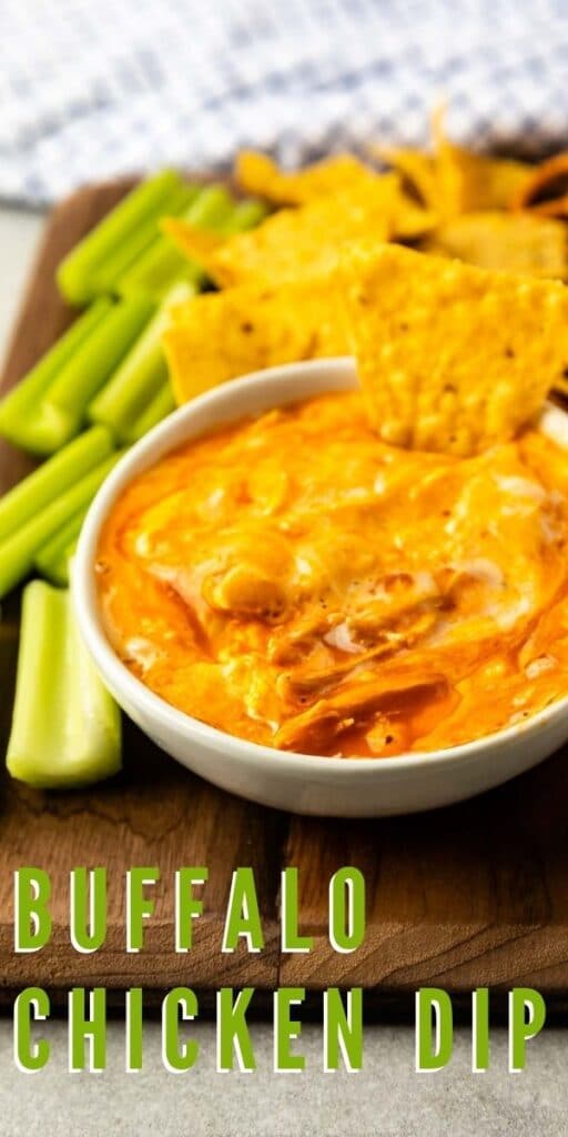 Buffalo chicken dip in a small bowl surrounded by chips, pretzels, carrots and celery and recipe title on bottom of photo