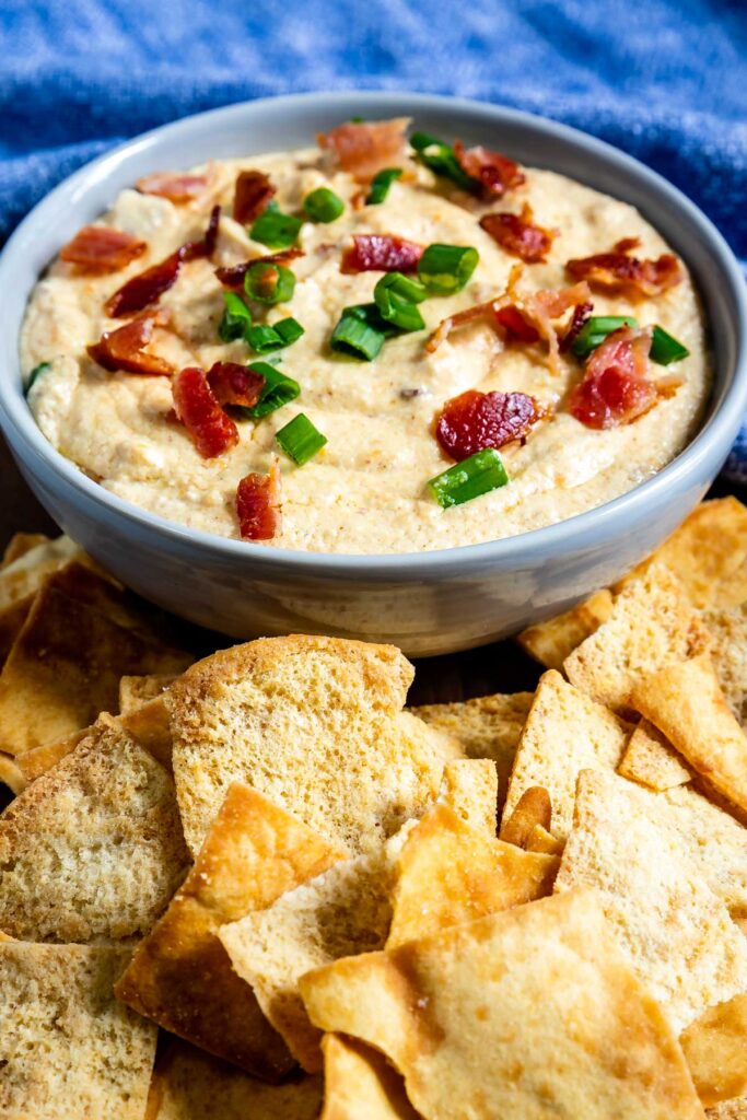 Crockpot cheesy bacon beer dip in a bowl surrounded by pita chips