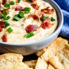 Crockpot cheesy bacon beer dip in a bowl surrounded by pita chips