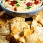 Crockpot cheesy bacon beer dip in a bowl surrounded by pita chips with recipe title on bottom of photo