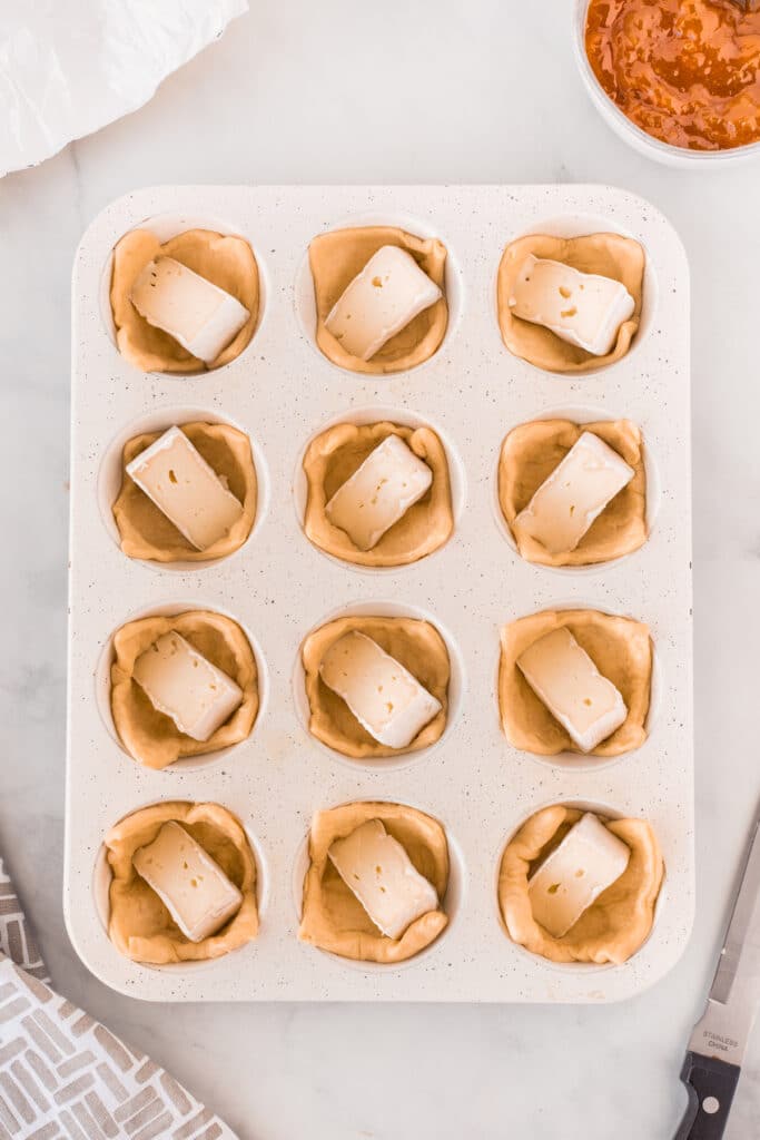 Overhead shot of process of making peach brie bites with brie cheese in puff pastry
