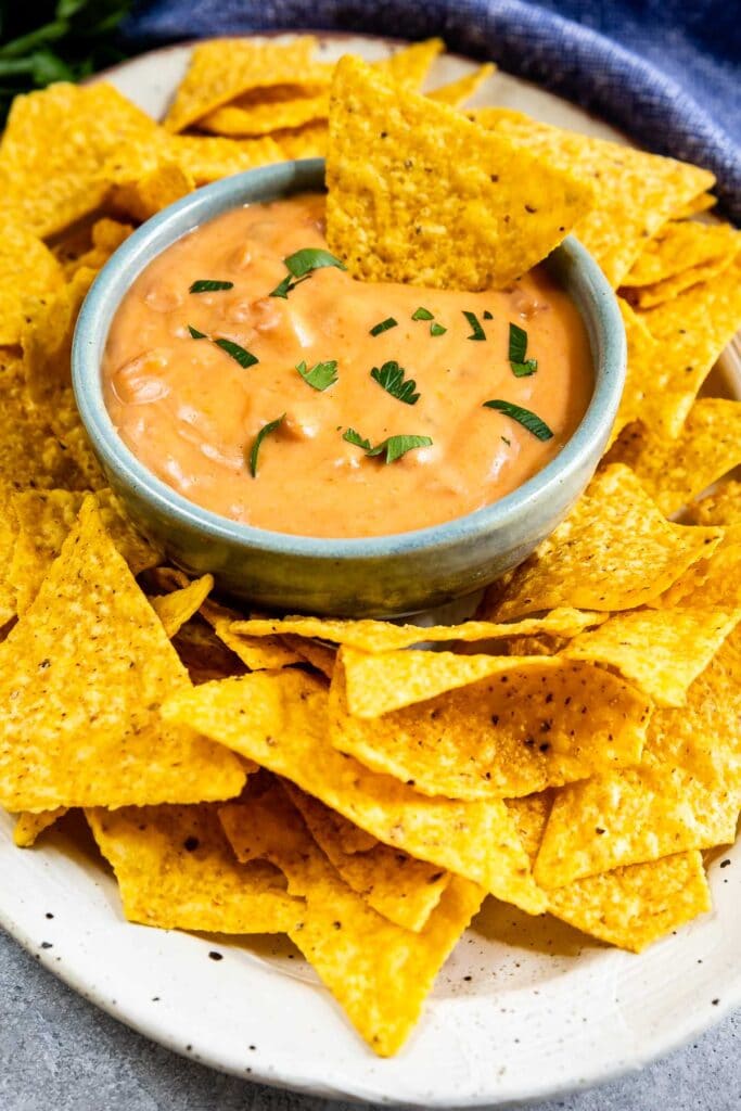 One chip being dipped into spicy bean dip with more all around the dip