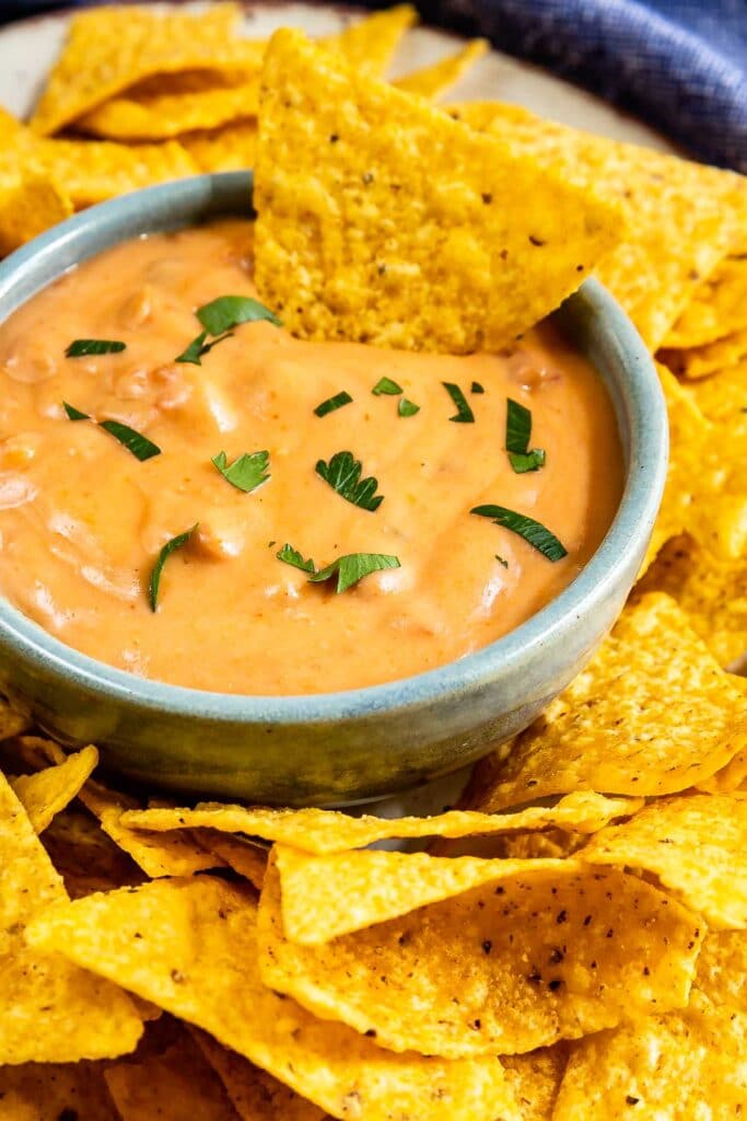 One chip being dipped into spicy bean dip with more all around the dip