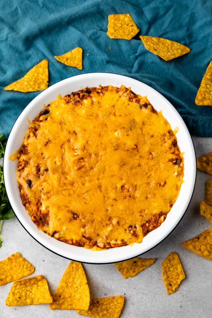 Overhead shot of chili cheese dip in a bowl surrounded by tortilla chips