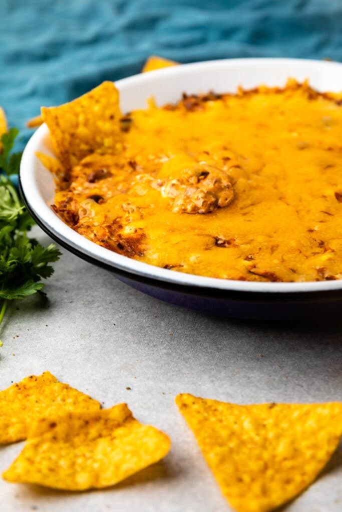 Close up side shot of chili cheese dip with a couple chips on the side