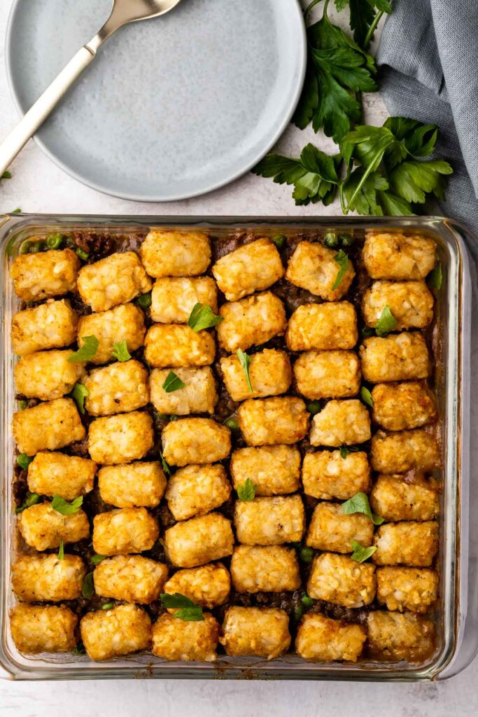 Overhead shot of tater tot bake in casserole dish next to a fork and plate