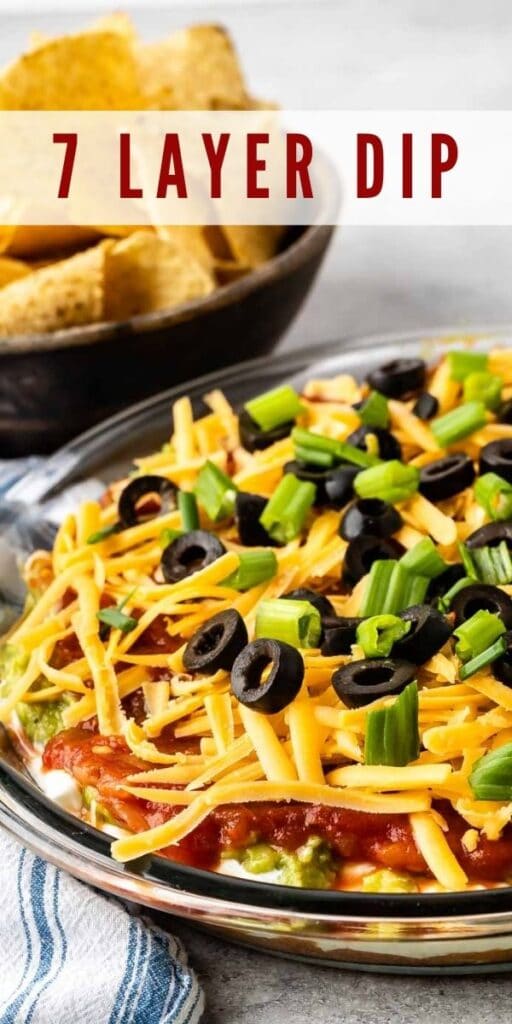 7 layer dip in a glass casserole dish with tortilla chips behind it with the recipe title on top of image