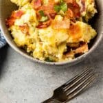 Cheese and bacon smashed potatoes in a bowl with recipe title on bottom of photo