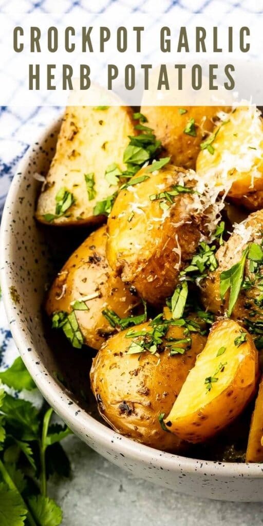 Overhead close up shot of crockpot garlic herb potatoes in a serving bowl topped with parmesan cheese and parsley with recipe title on top of image