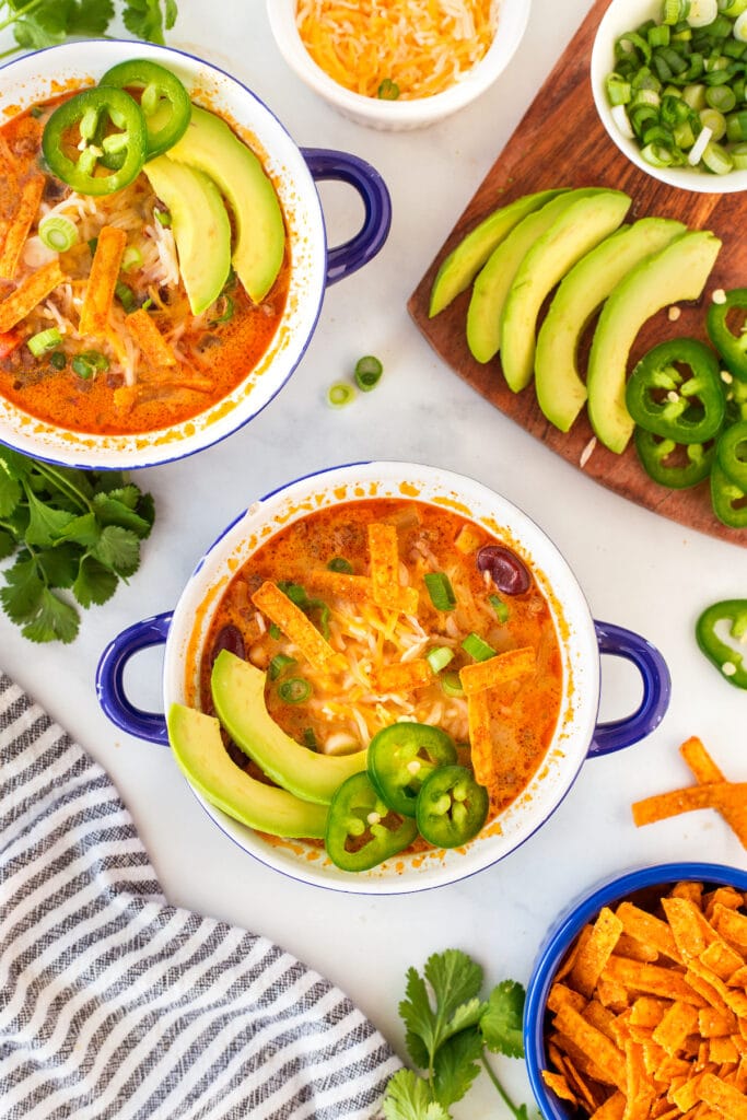 Overhead shot of taco soup in small bowls topped with avocado, jalapeno and tortilla strips