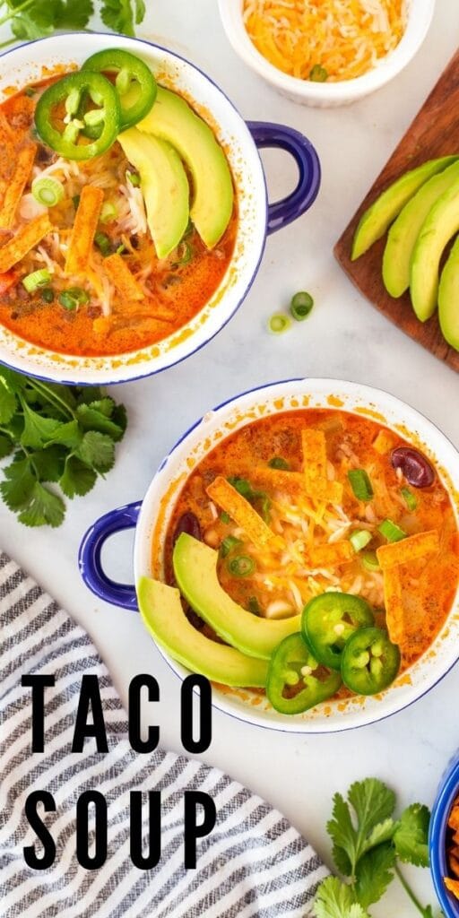 Overhead shot of taco soup in small bowls topped with avocado, jalapeno and tortilla strips and recipe title on bottom of photo