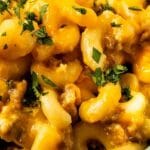 Close up overhead shot of crockpot mac n cheese with sausage and recipe title on top of image
