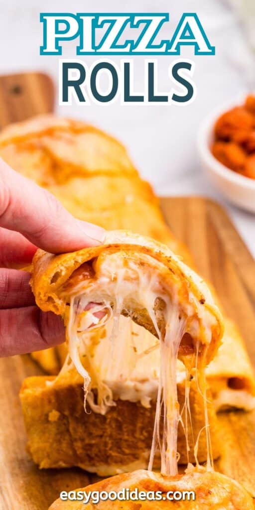 A hand savors the gooey goodness of a cheesy pizza roll, as melted cheese stretches invitingly. Set on a wooden board, with a bowl of pepperoni nearby, the scene is topped with Pizza Rolls and underscored by easygoodideas.com.