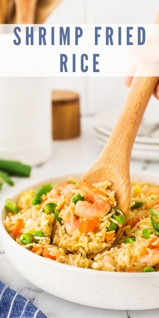 Shrimp fried rice in a serving bowl with wooden serving spoon with recipe title on top of image