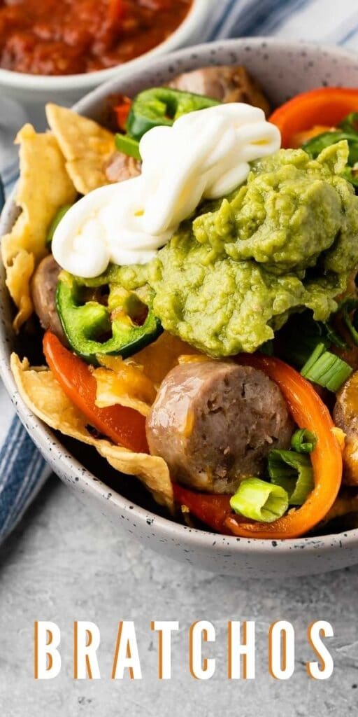 Bowl full of bratchos topped with sour cream and guacamole with recipe title on bottom of photo