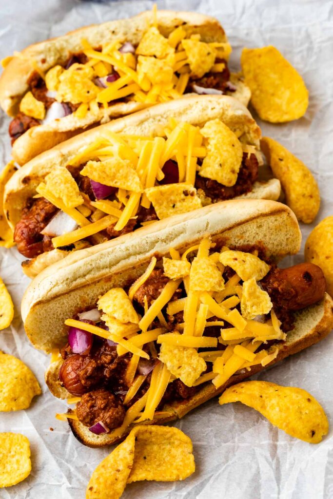 Three chili dogs topped with cheese and frito chips