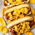 Three chili dogs topped with cheese and frito chips with recipe title on bottom of photo
