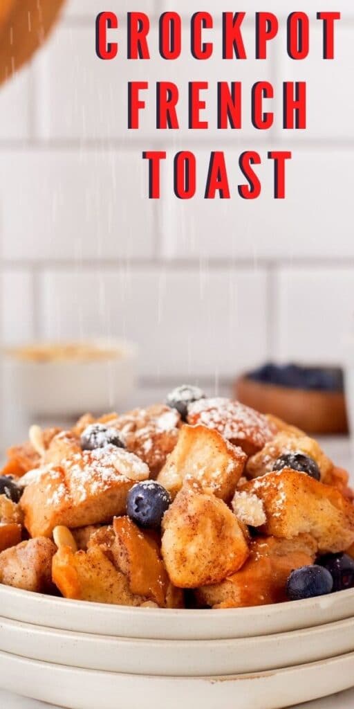 Plate full of crockpot french toast, topped with blueberries and powdered sugar with recipe title on top of image